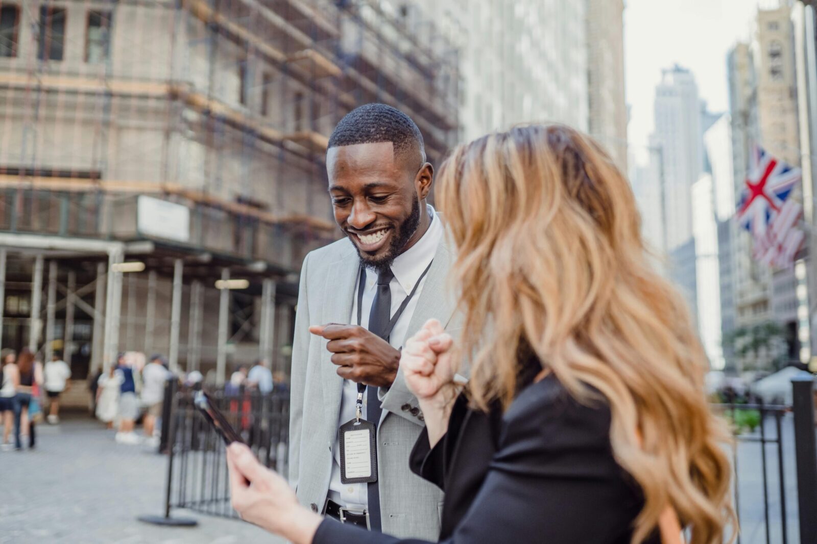 Two business professionals engage in lively conversation on an urban street, sharing insights.