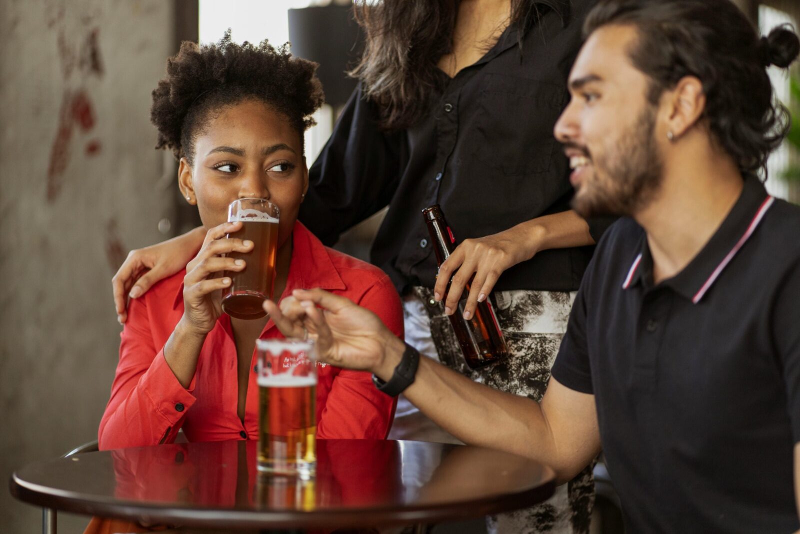 A group of friends socializing over drinks at an indoor pub setting. Casual and relaxed atmosphere.