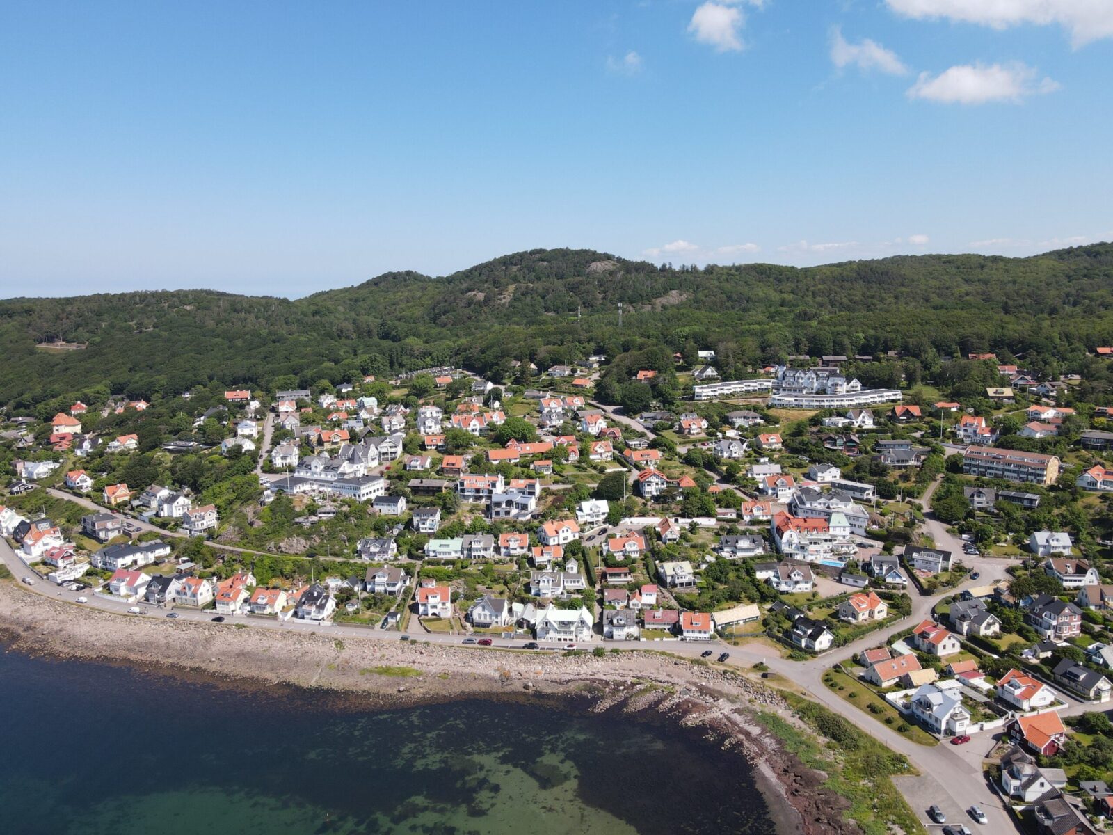 Aerial view of the picturesque coastal village of Höganäs in Skåne, Sweden, with charming houses and lush greenery.